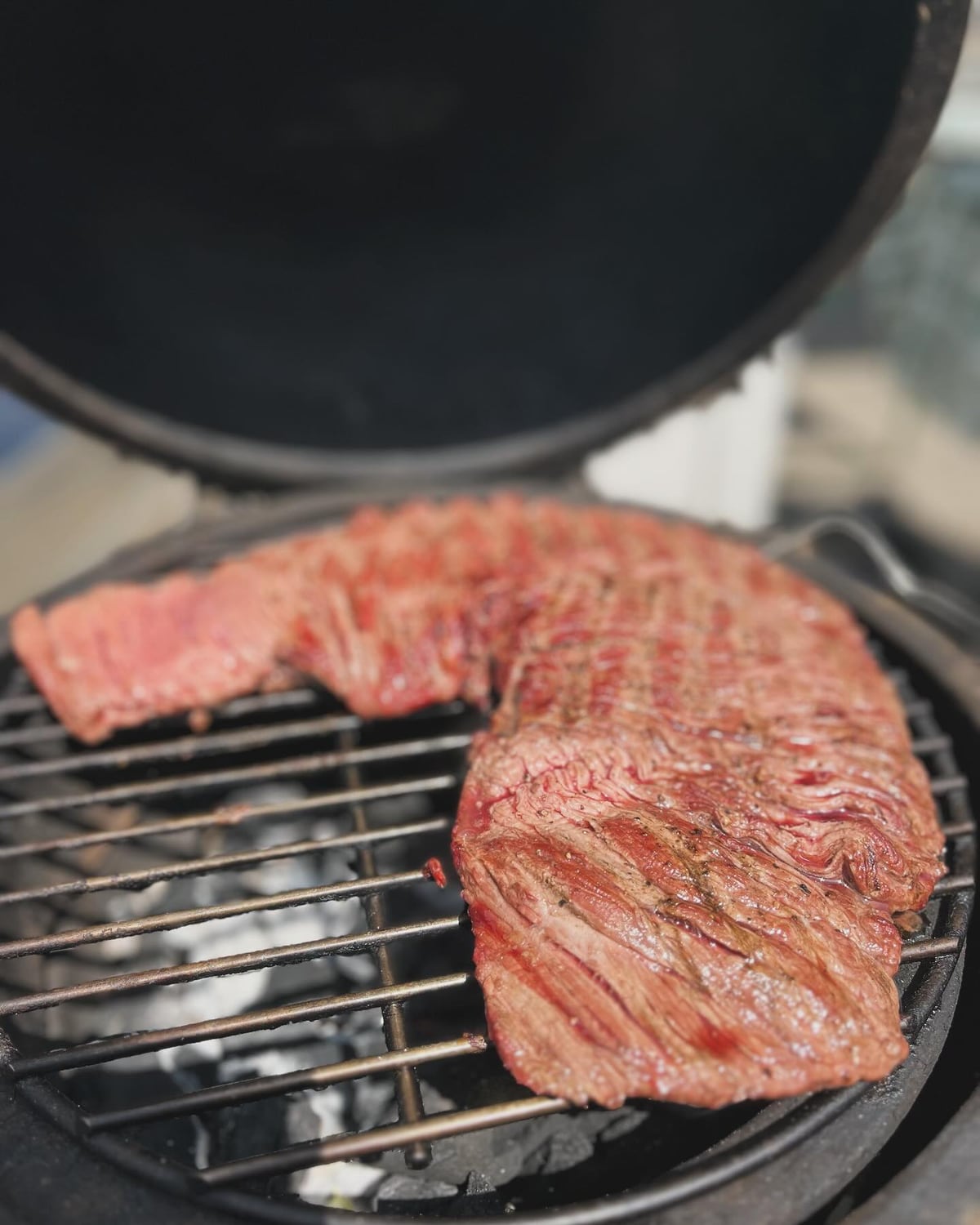 Een stuk rundvlees op het rooster van een kamado